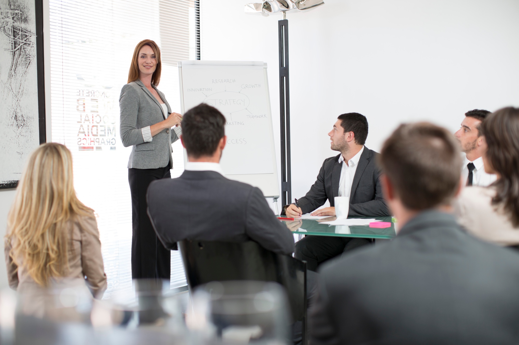 Businesswoman in boardroom leading a meeting with flip chart