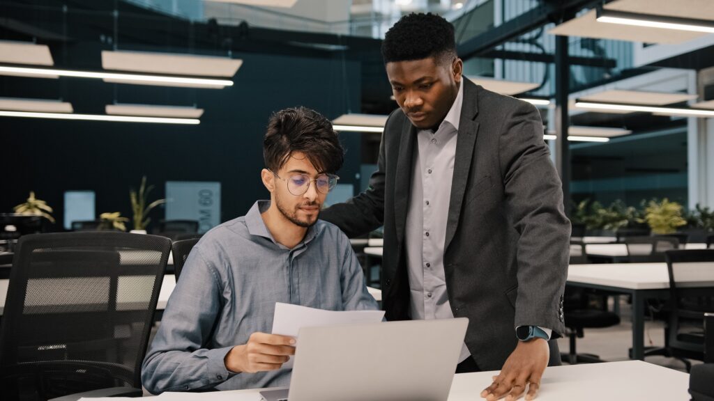 Male african mentor financial advisor businessman boss helping arab man colleague discussing